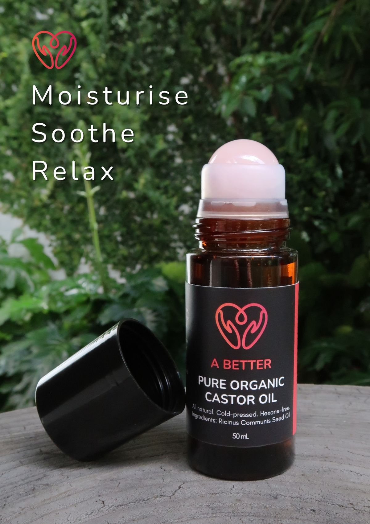 Bottle of A Better Pure Organic Castor Oil with a roller ball on a wooden surface with greenery in the background.